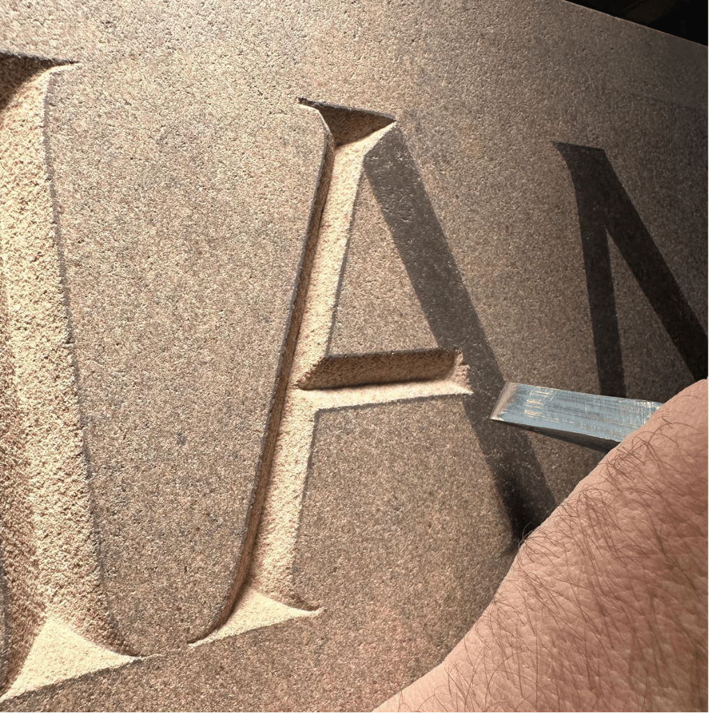 Close-up of a hand-cut serif letter showing its shape and depth