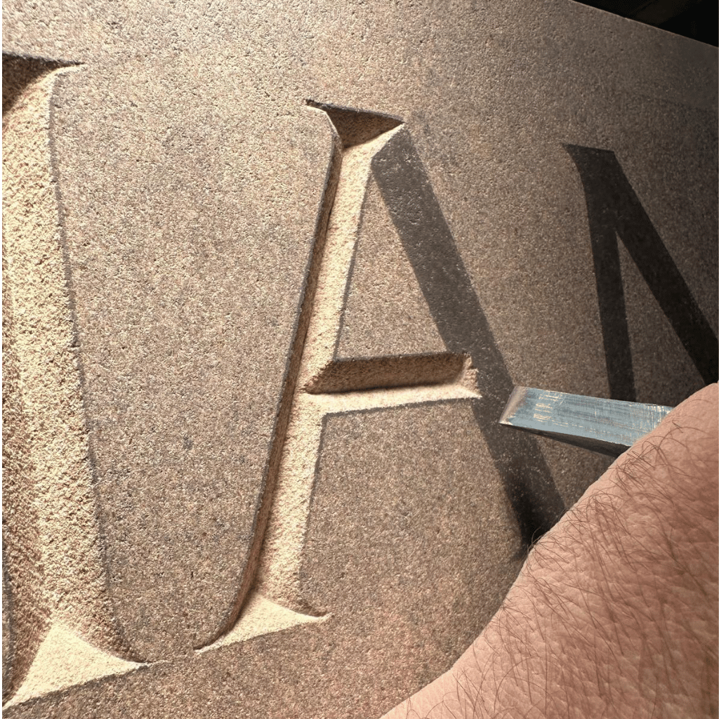 Close-up of a memorial mason hand-cutting a serif letter into stone
