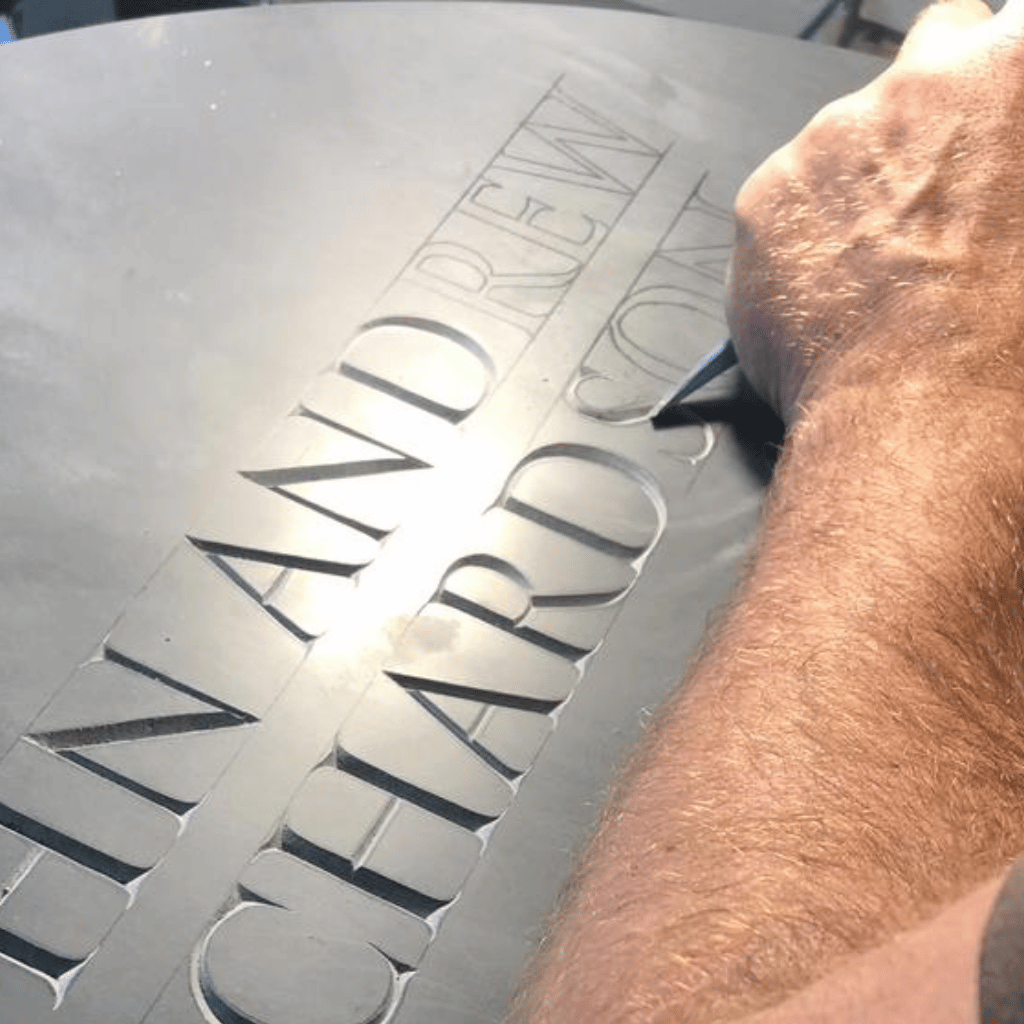 A memorial mason carving outlined lettering into a stone memorial